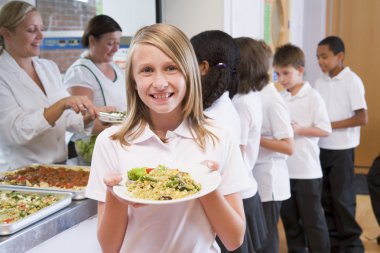 Schoolgirl holding plate of lunch in school cafeteria clipart