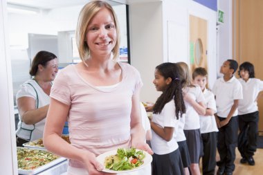 Teacher holding plate of lunch in school cafeteria clipart