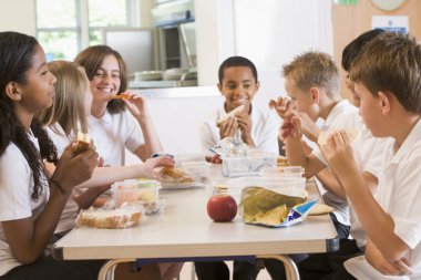 Schoolchildren enjoying their lunch in a school cafeteria clipart