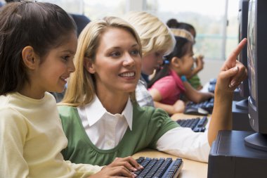 Teacher helping kindergarten children learn how to use computers clipart