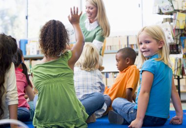 Kindergarten teacher reading to children in library, girl lookin clipart