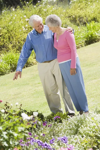 高级夫妇在欣赏花的花园 — 图库照片