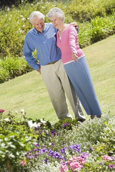 花壇に見とれながら庭に年配のカップルの立っています — ストック写真
