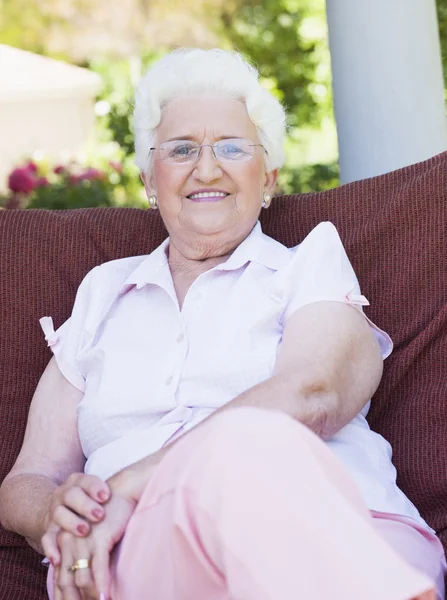 Starszy Kobieta Siedzi Krzesło Ogrodowe Uśmiechając Się Kamery — Zdjęcie stockowe