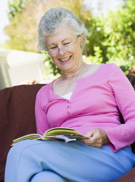 Oudere vrouw die buiten boek leest — Stockfoto