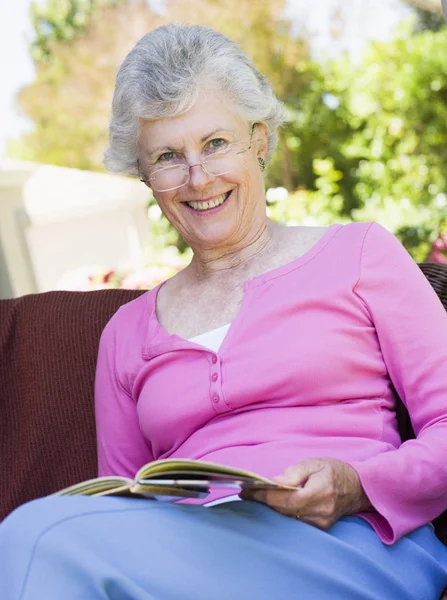 Oudere vrouw die buiten boek leest — Stockfoto