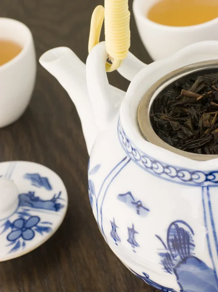 Hojas de té verde en una olla de té con tazas —  Fotos de Stock