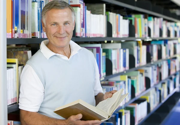 Starší muž čtení v knihovně — Stock fotografie