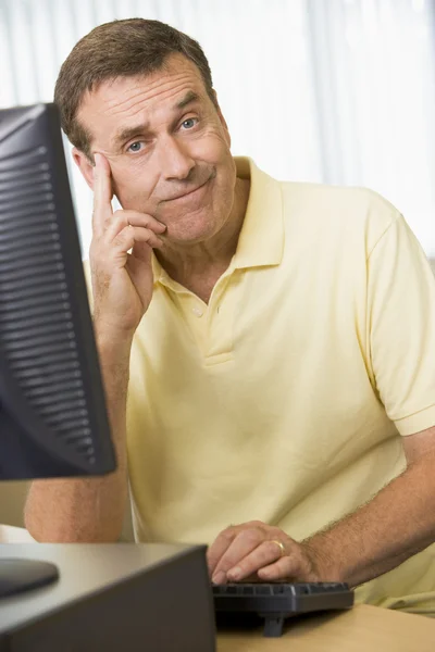 Un hombre confuso trabajando en una computadora — Foto de Stock