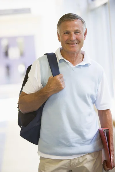 Ein Mann mit Rucksack steht in einem Campus-Korridor — Stockfoto