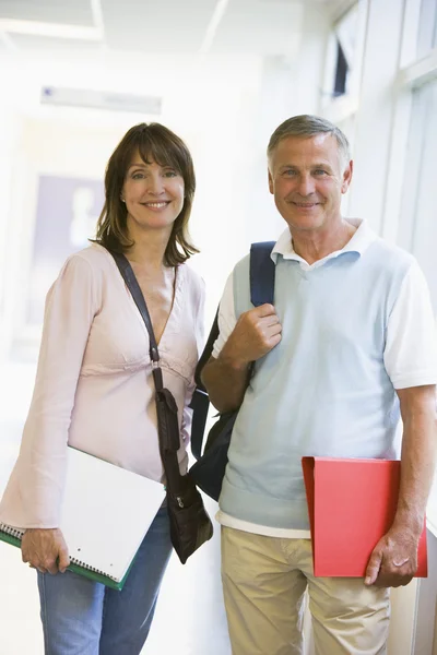 En man och kvinna med ryggsäckar stående i en campus korridor — Stockfoto