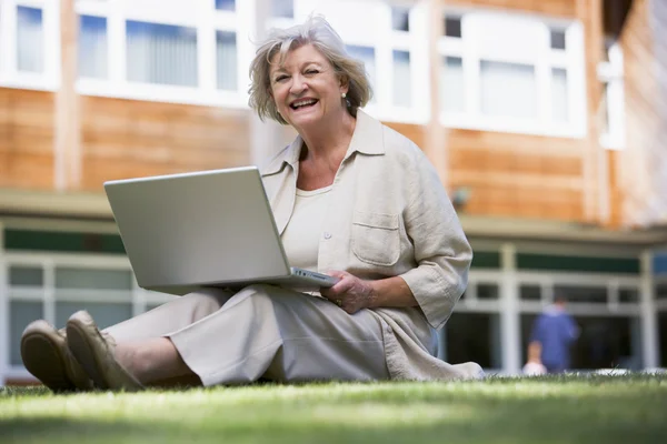 Starszy kobieta korzysta z laptopa na kampusie — Zdjęcie stockowe