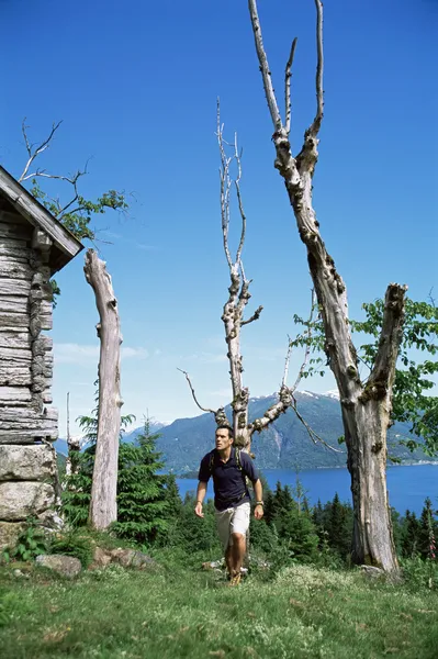 Muž turistiku až k dřevěné boudě — Stock fotografie