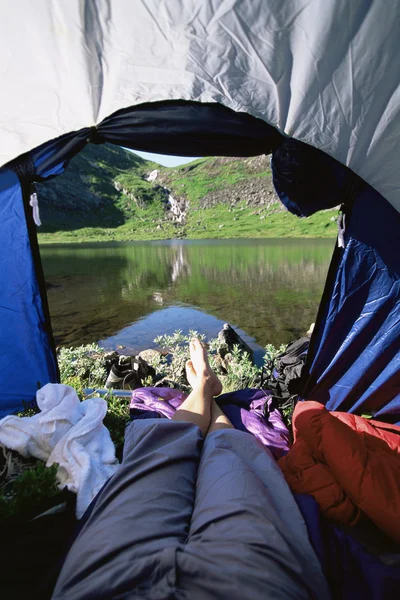 Mulher deitada na tenda com vista para o lago — Fotografia de Stock