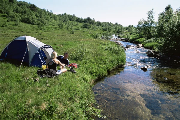 Couple camping next to stream — Stock Photo, Image
