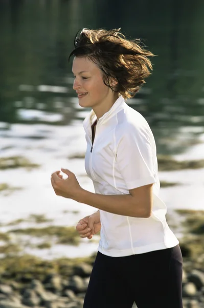 Jonge vrouw loopt langs de rand van water — Stockfoto