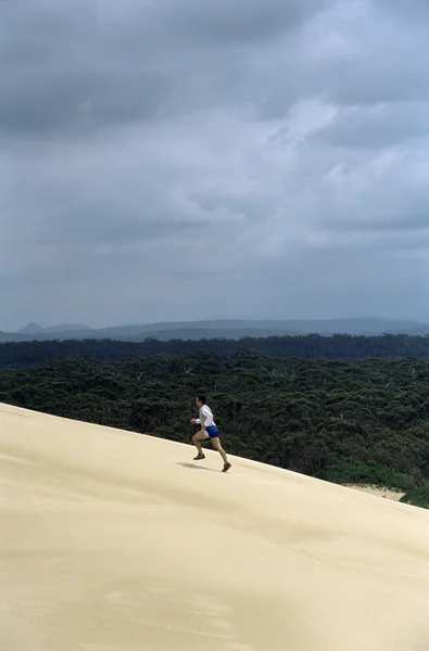 Человек бежит по песчаной дюне — стоковое фото