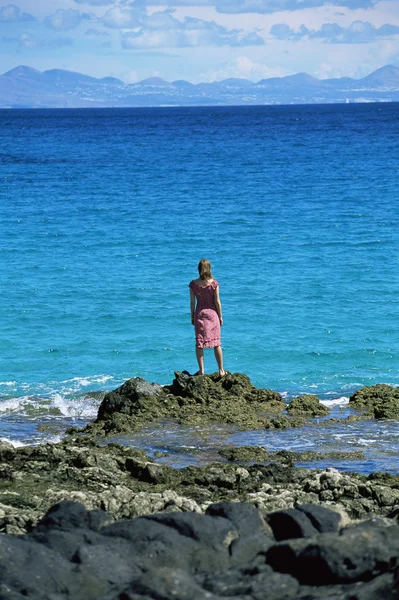 年轻女子站立岩石上 望着大海 — 图库照片