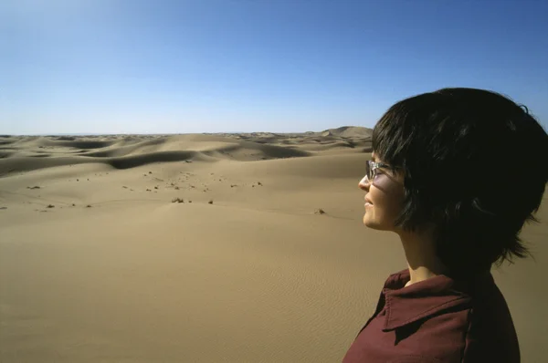 Молодая женщина смотрит через песчаные дюны — стоковое фото