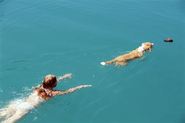 Jeune femme nageant avec chien , — Photo