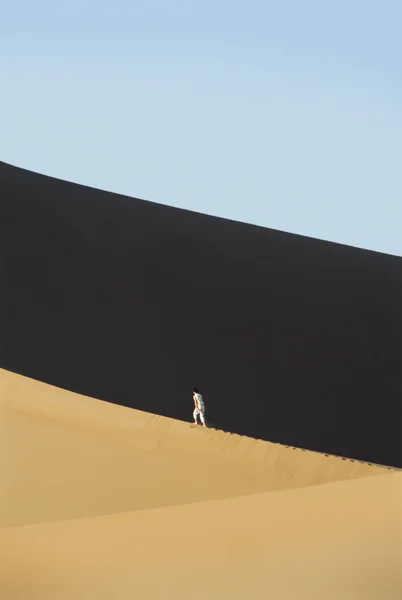 stock image Woman walking across desert sand dunes