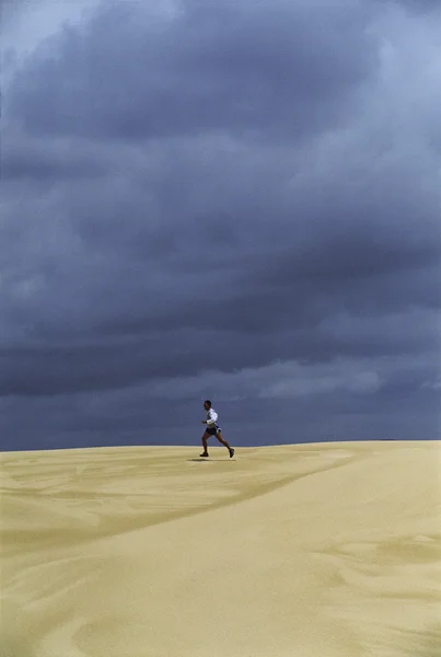 Человек бежит по песчаным равнинам — стоковое фото