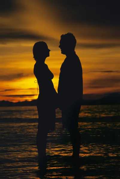 Silhueta de casal de pé cara a cara na praia ao pôr do sol — Fotografia de Stock