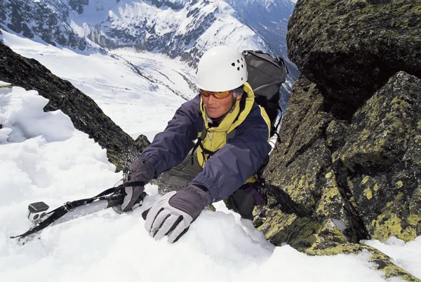 Bergsteiger klettert mit Eispickel einen steilen Hang hinauf — Stockfoto