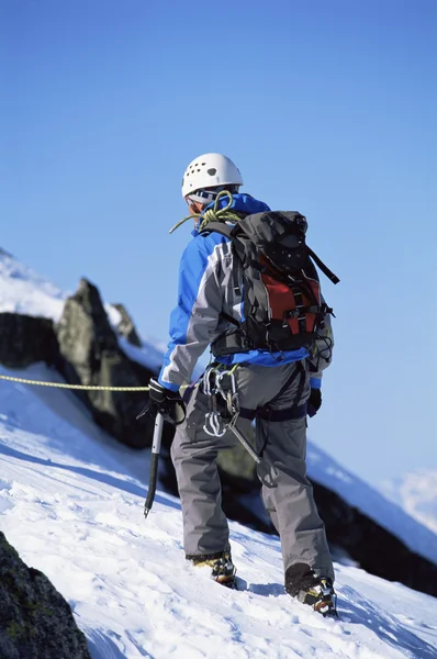 Jovem montanhês escalando no pico nevado — Fotografia de Stock