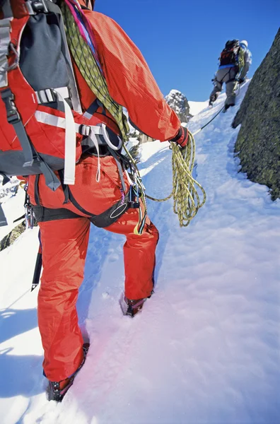 年轻男子登山上白雪皑皑的山顶 — 图库照片