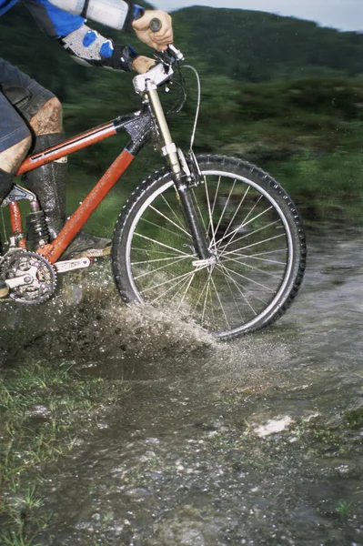 Гірський велосипедист перетинає потік — стокове фото
