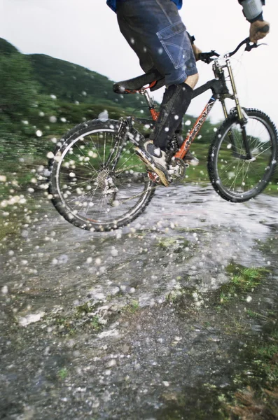 Mountainbike-åkaren hoppa över ström — Stockfoto