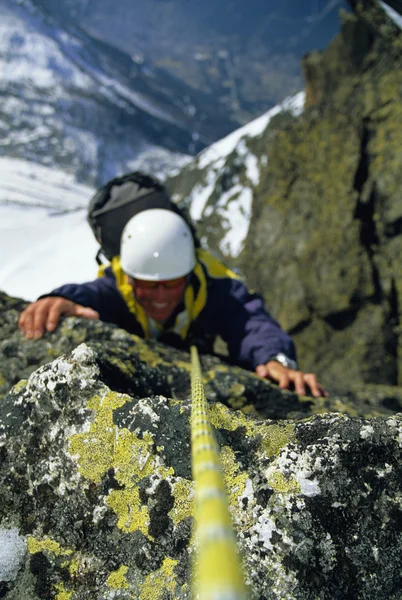 Bergsteiger erklimmt verschneite Felswand — Stockfoto