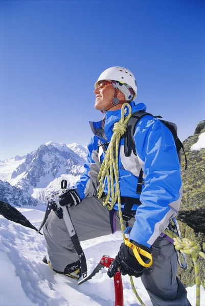 Jovem montanhês escalando no pico nevado — Fotografia de Stock