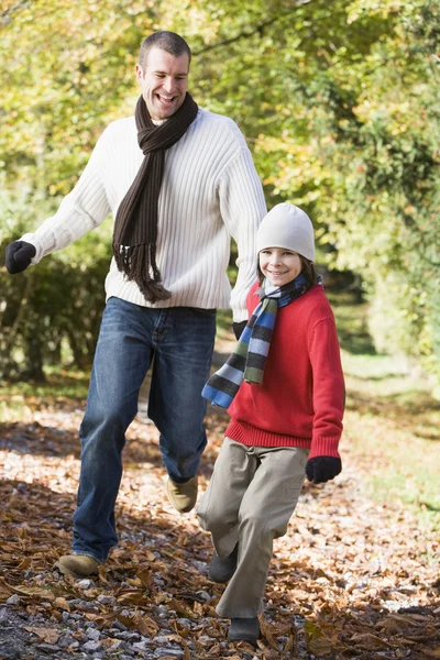 Padre e hijo corriendo por el camino del otoño — Foto de Stock