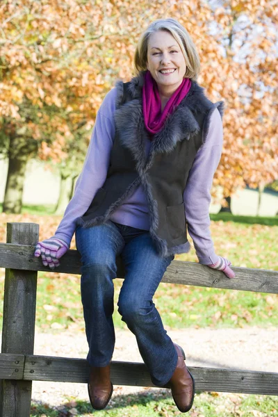 Senior mulher sentada na cerca — Fotografia de Stock