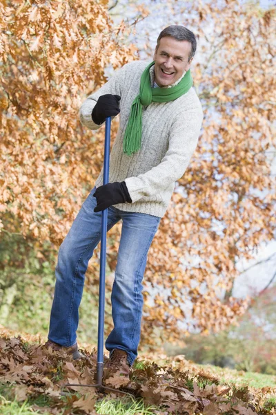 Senior räumt Herbstlaub auf — Stockfoto