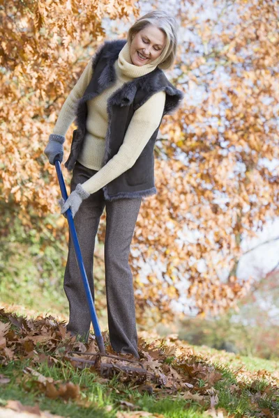 Mulher Sênior Arrumando Folhas Outono Jardim — Fotografia de Stock