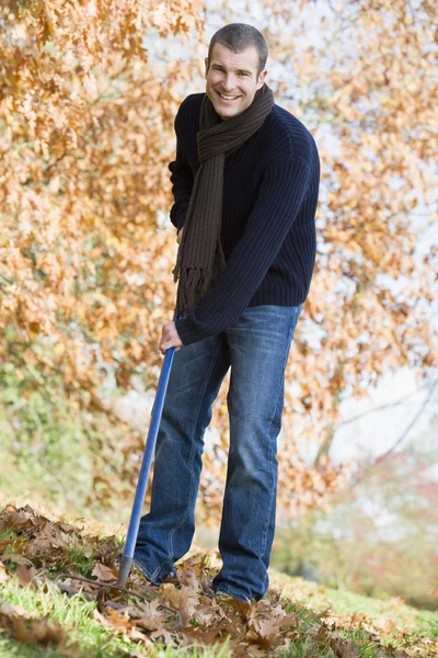 Young man clearing autumn leaves — Stock Photo, Image