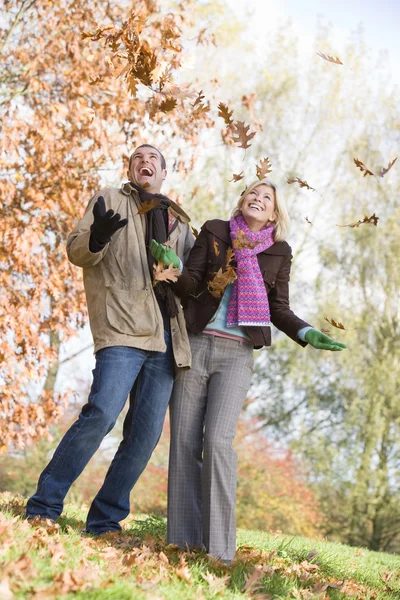 Молодая пара веселится с осенними листьями — стоковое фото
