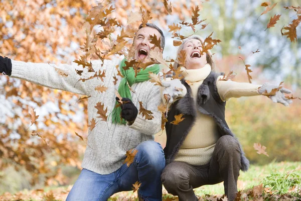 高级夫妇投掷秋季叶片在空气中 — 图库照片