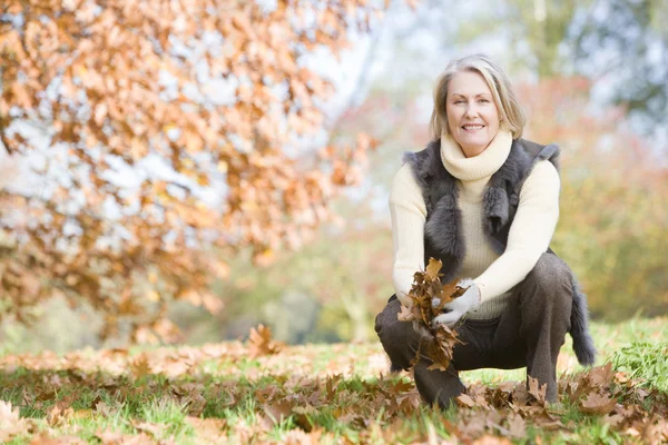Seniorin Sammelt Herbstlaub Auf Spaziergang — Stockfoto