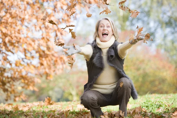 高级女子投掷秋季叶片在空气中 — 图库照片