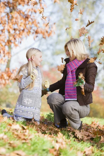 Mor och dotter kasta löv i luften — Stockfoto