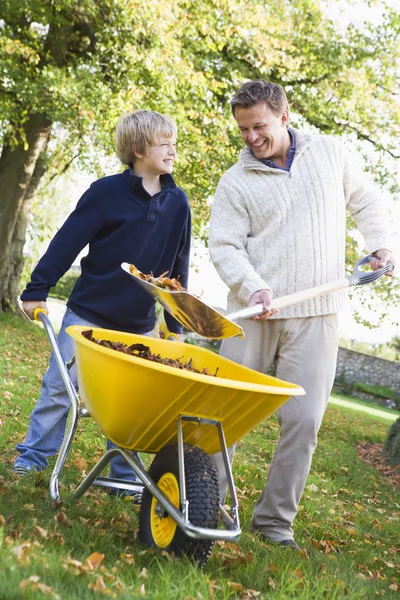 Filho ajudando pai coletar folhas — Fotografia de Stock