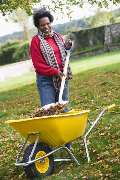 Mogen kvinna samla löv i trädgården — Stockfoto