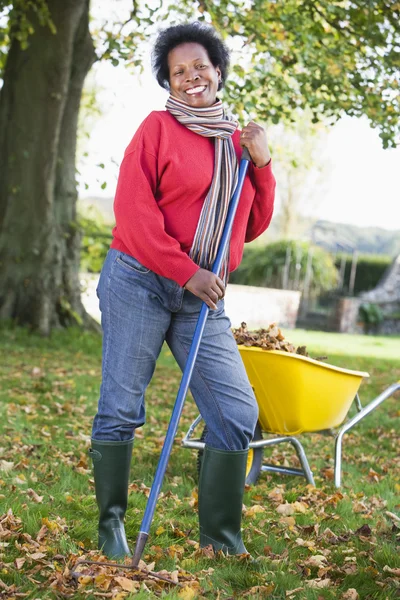 Olgun kadın bahçede yaprakları toplamaya — Stok fotoğraf