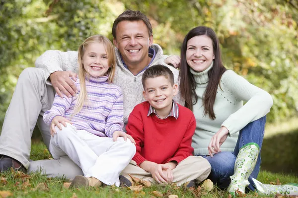 Familjen sitter bland höstträd — Stockfoto