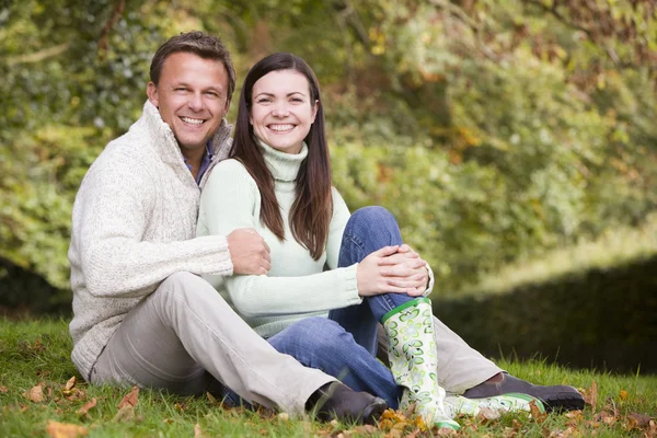坐在秋天树林对年轻夫妇 — 图库照片