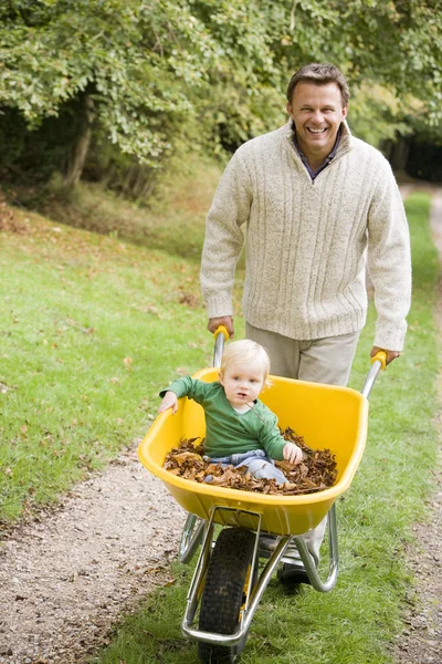 Father pushing young son in wheelbarrow — Stock Photo, Image